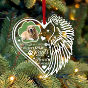 Heart-shaped ornament with a dog's photo and angel wings on a Christmas tree.