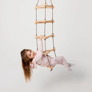 Child playing with a wooden climbing ladder on a plain background