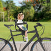 Child sitting in a bicycle seat with a blurred green outdoor background