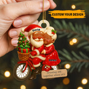 Personalized Christmas ornament with Santa and a woman on a bike, against a festive background.
